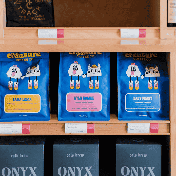 Blue CREATURE COFFEE bags with cartoon characters on a store shelf in grocery store. Coffee beans! 