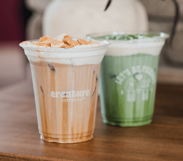 Two drinks from Creature Coffee Co. on a wooden espresso bar at an event 