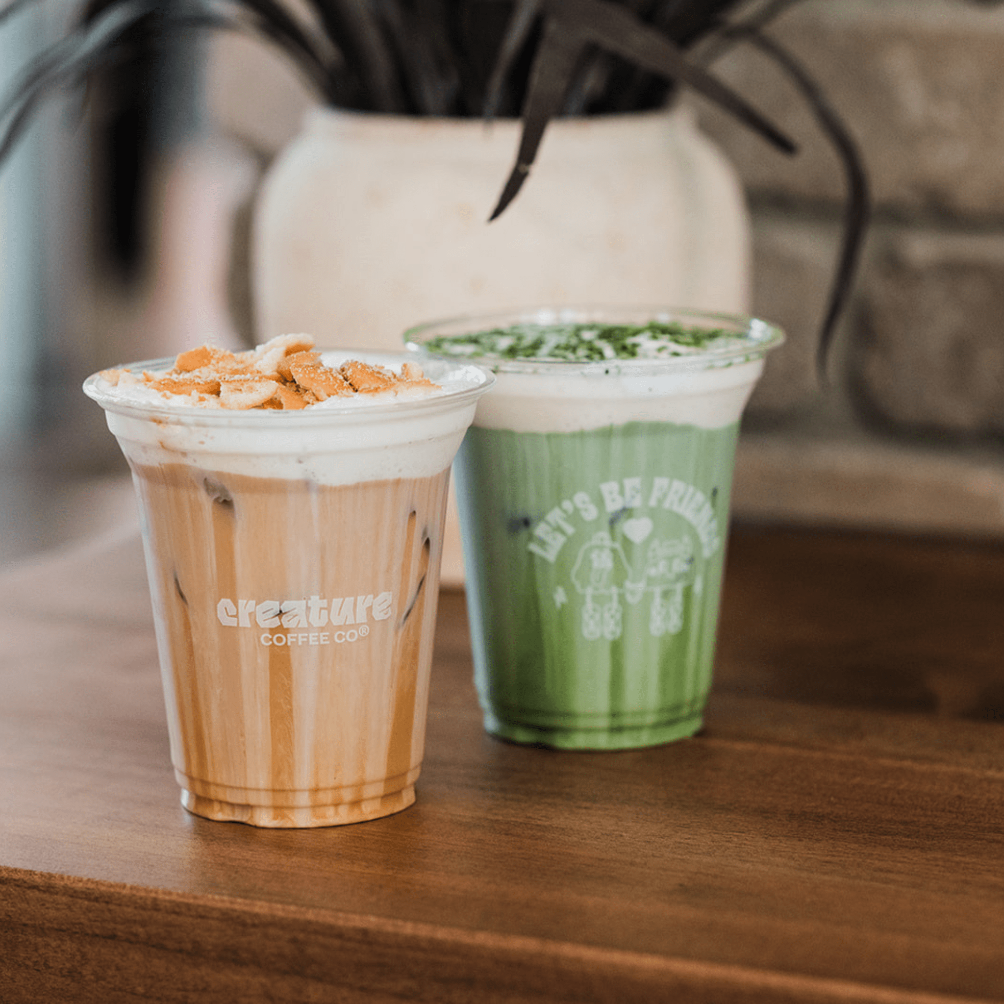 Two drinks in clear plastic cups on a wooden surface with a blurred background