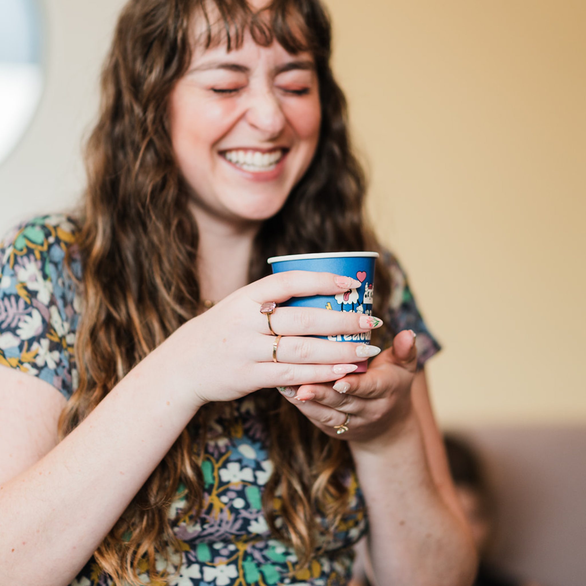 Woman holding a blue cup with a pattern, smiling.
