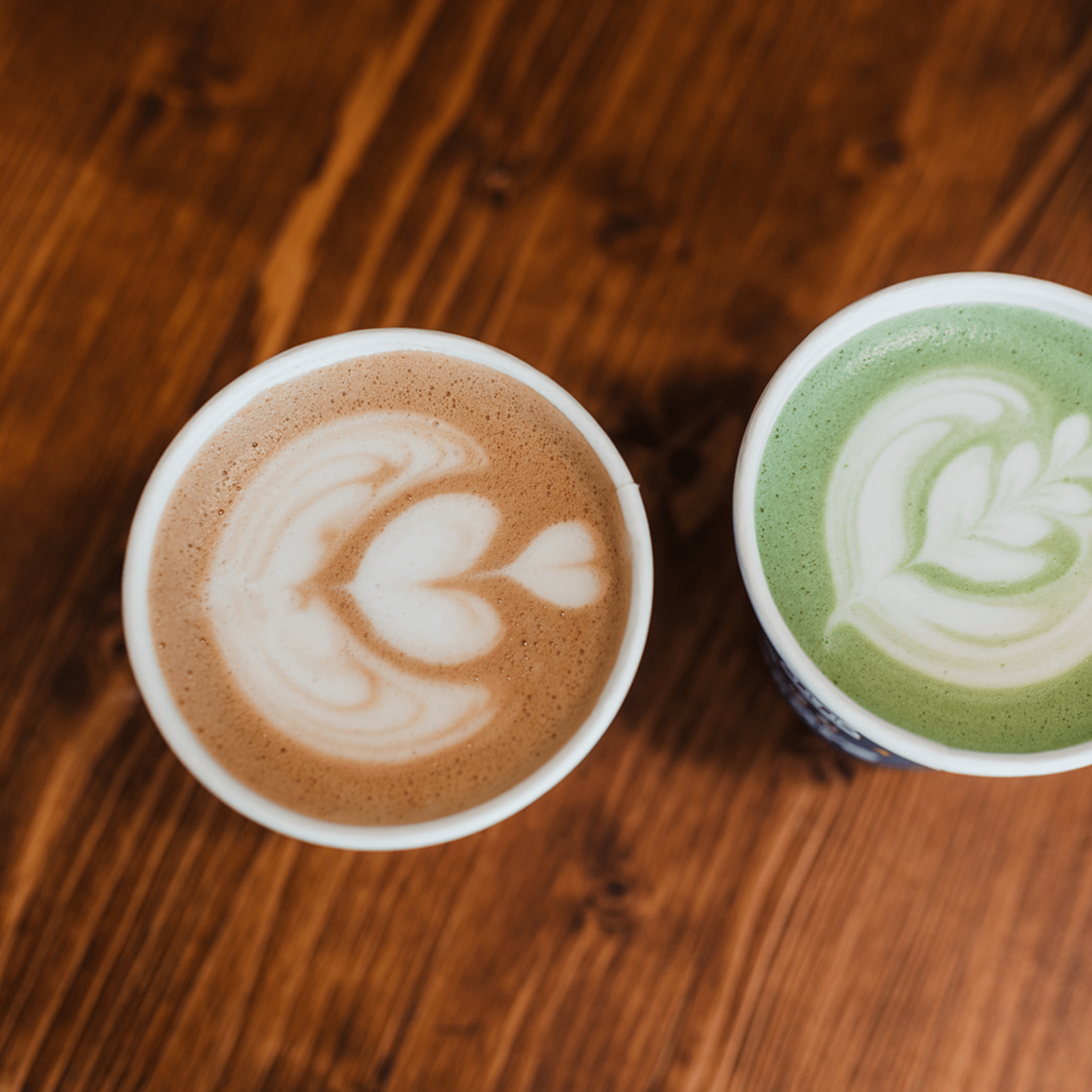 Two cups of coffee with latte art on a wooden mobile coffee cart bartop 