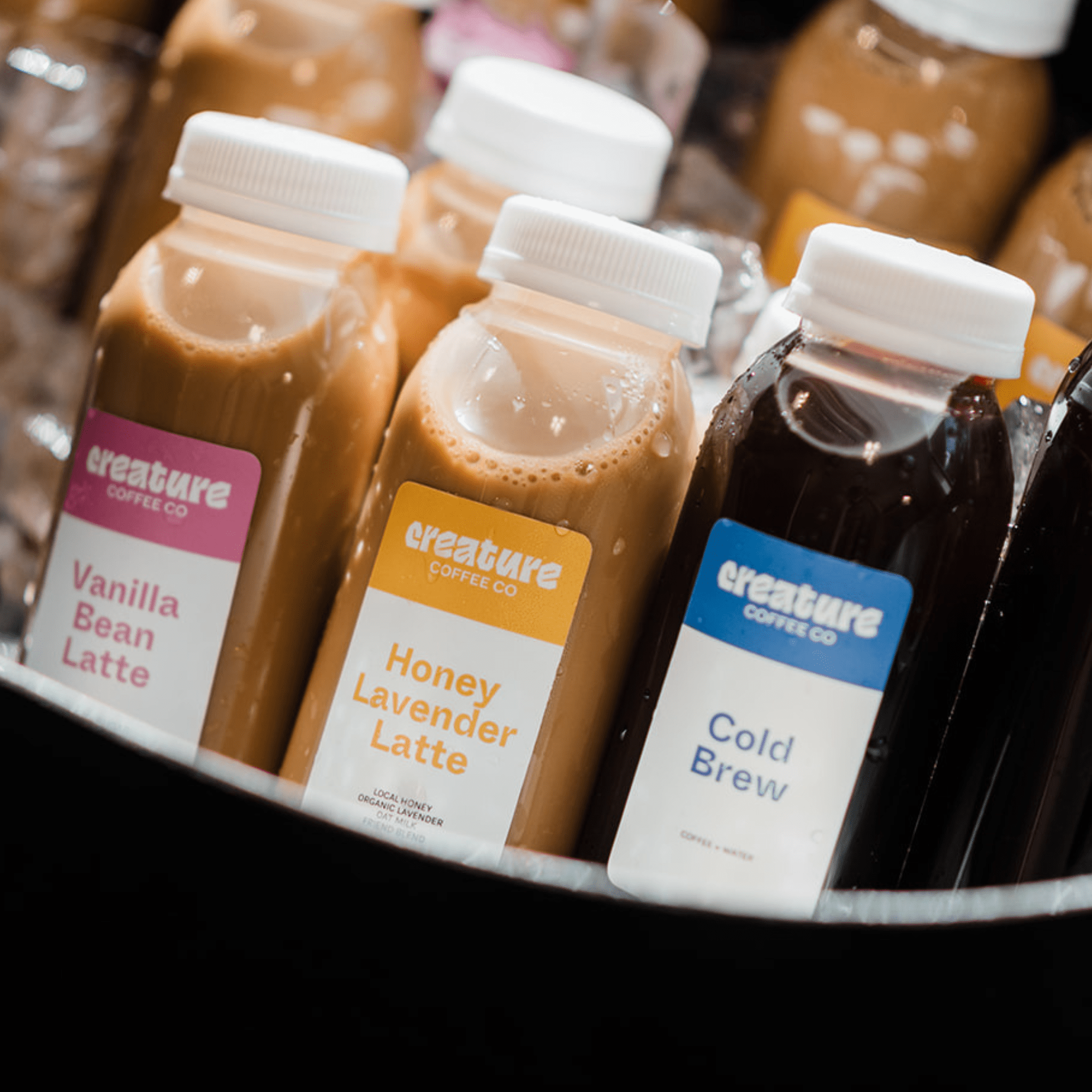 Compostable bottles of 'creature coffee co' drinks with visible labels in a display.