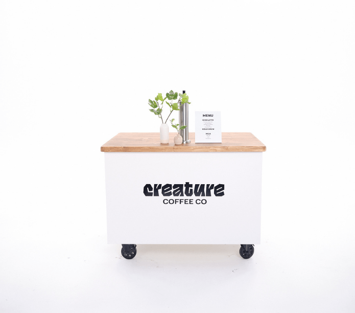 Coffee cart with 'creature coffee co' branding on a white background