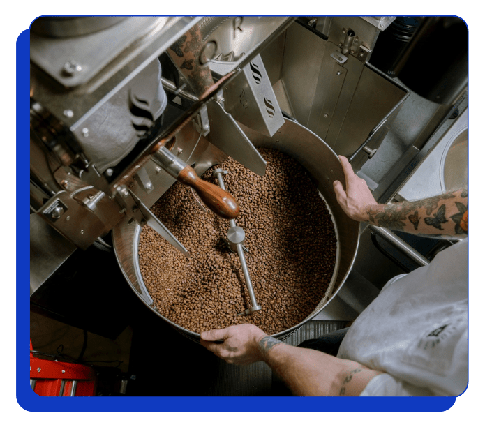 Person operating a coffee roasting machine with coffee beans inside