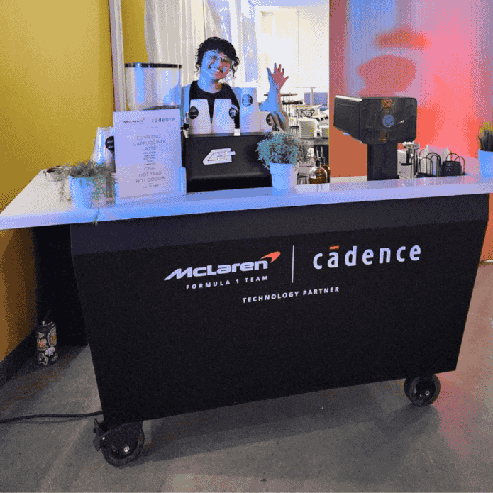 Barista standing behind a custom coffee cart with McLaren and Cadence branding