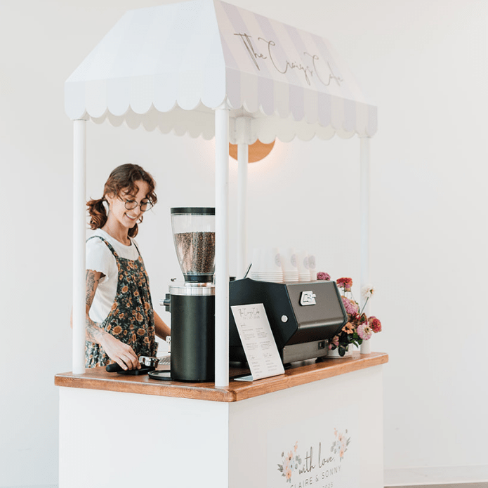 Small mobile coffee shop counter with a coffee machine and a person behind the counter, branded 'The Coffee Co'.