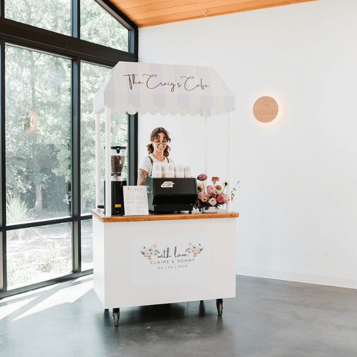 Small cafe cart with branding inside a modern building, custom coffee cart for a wedding serving espresso drinks to people at a wedding event in Austin TX