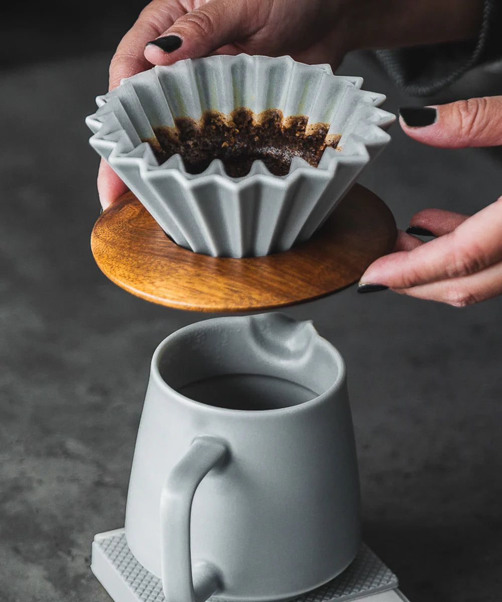 Person using a manual coffee Origami Dripper Pour Over with a focus on the process of brewing coffee at home. 